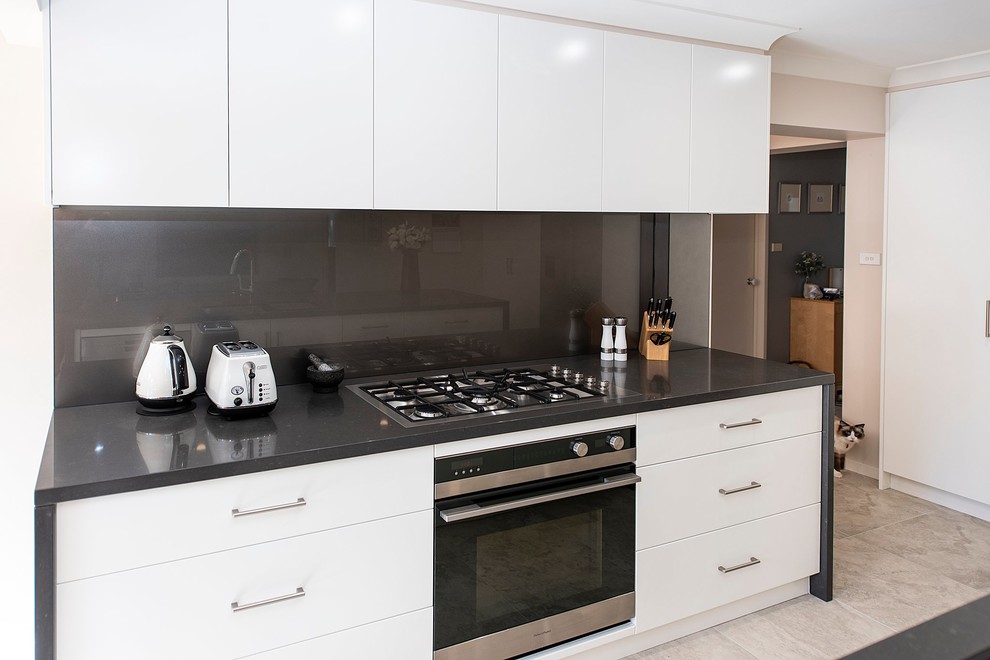 Inspiration for a large contemporary open plan kitchen in Sydney with an undermount sink, flat-panel cabinets, white cabinets, quartz benchtops, metallic splashback, glass sheet splashback, stainless steel appliances, porcelain floors, with island, grey floor and grey benchtop.