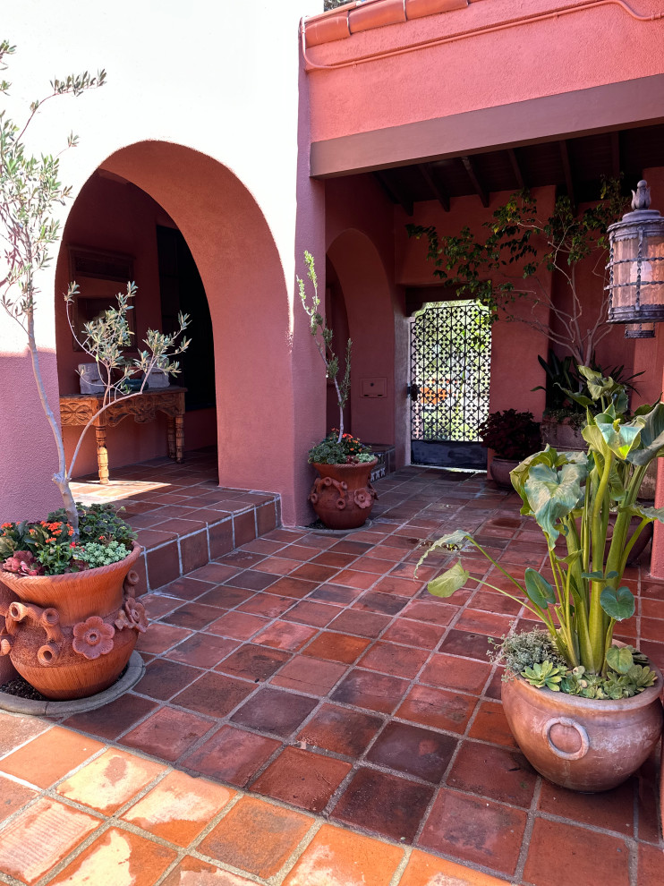 Immagine di un patio o portico mediterraneo di medie dimensioni e in cortile con un giardino in vaso, piastrelle e nessuna copertura
