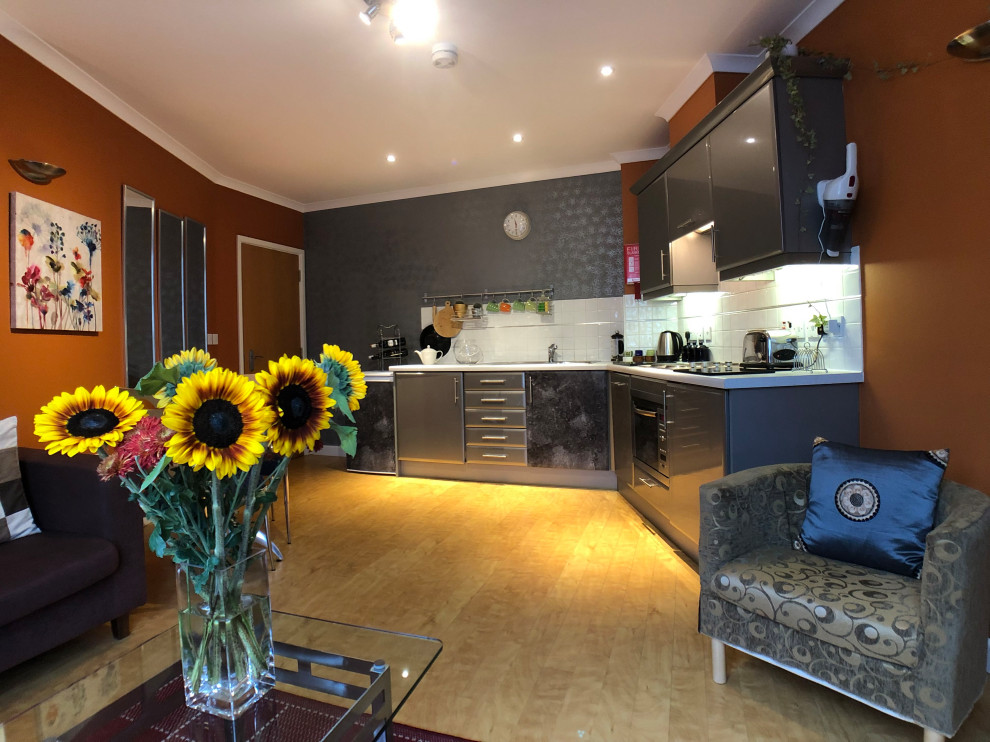 Inspiration for a small modern single-wall eat-in kitchen in Berkshire with an integrated sink, flat-panel cabinets, grey cabinets, solid surface benchtops, white splashback, terra-cotta splashback, panelled appliances, vinyl floors, no island, yellow floor and white benchtop.