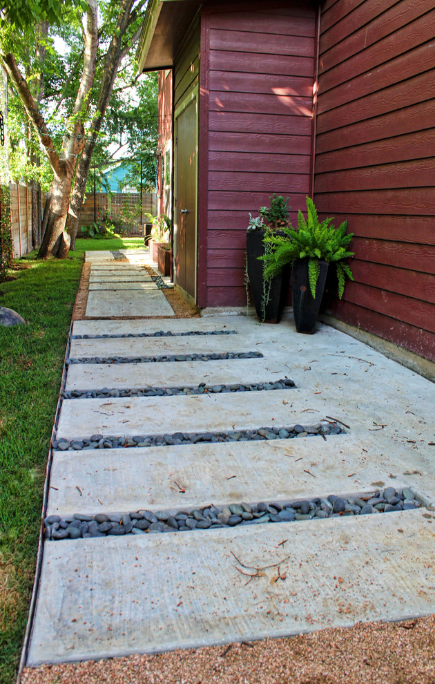 Photo of a mid-sized modern backyard garden for summer in Austin with a garden path and concrete pavers.