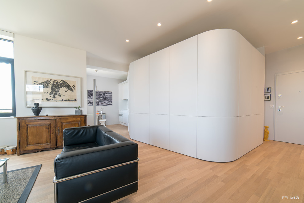 This is an example of a mid-sized contemporary open concept family room in Strasbourg with white walls, light hardwood floors, no fireplace, a freestanding tv and beige floor.