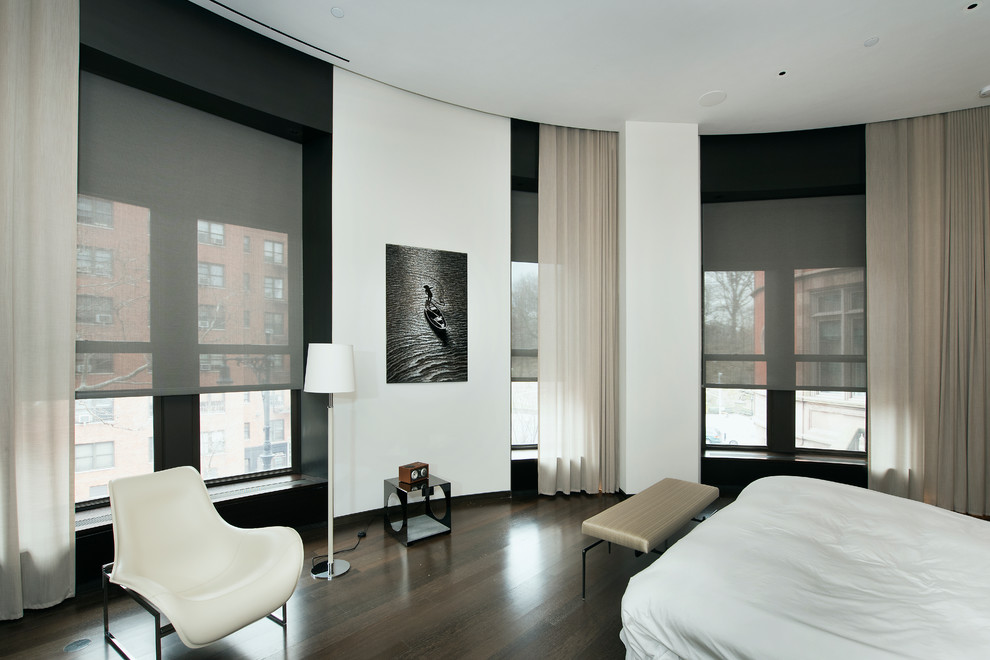 Photo of a large modern master bedroom in New York with white walls and dark hardwood floors.