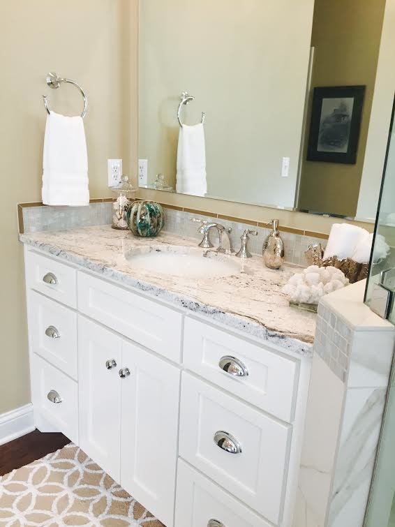 Inspiration for a mid-sized transitional master white tile and porcelain tile porcelain tile and brown floor corner shower remodel with an undermount sink, recessed-panel cabinets, white cabinets, granite countertops, a one-piece toilet, beige walls, a hinged shower door and multicolored countertops
