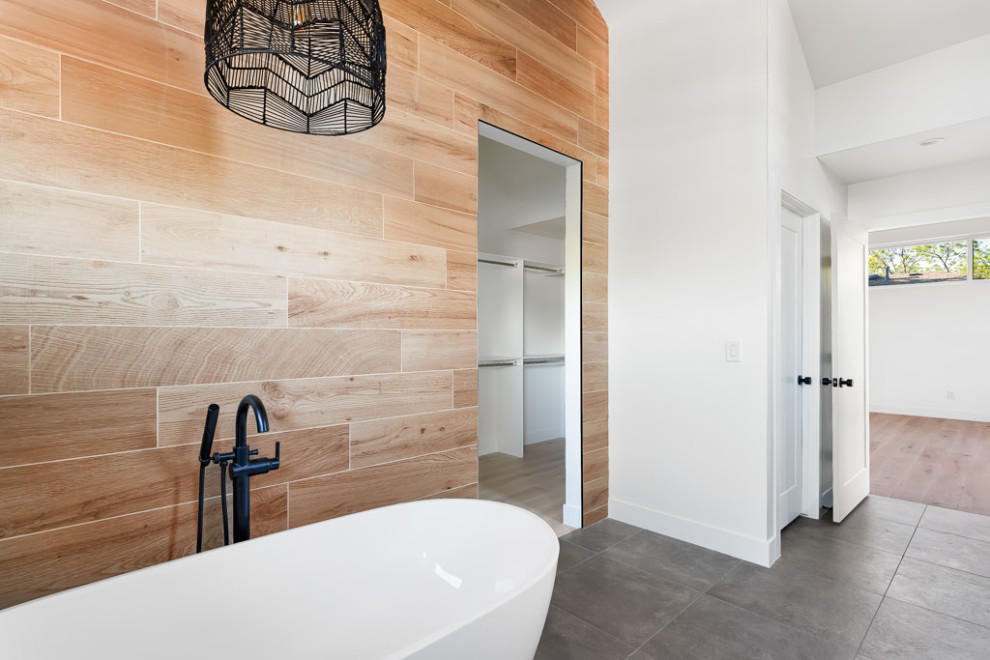 Photo of an industrial master bathroom in Denver with flat-panel cabinets, medium wood cabinets, a freestanding tub, a double shower, gray tile, cement tile, grey walls, porcelain floors, an undermount sink, quartzite benchtops, grey floor, a hinged shower door, white benchtops, a shower seat, a double vanity and a floating vanity.