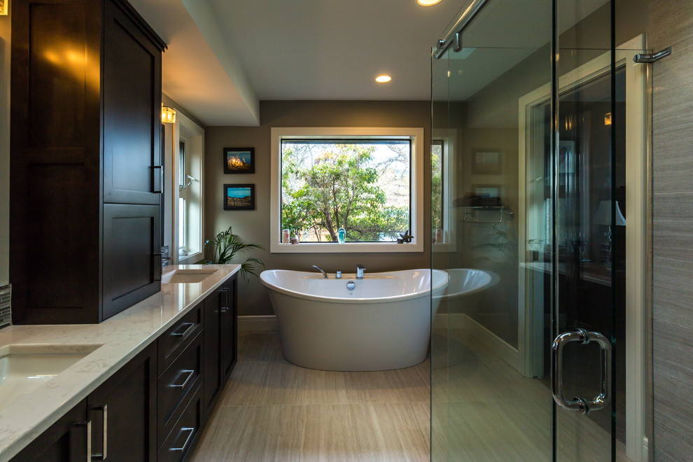 Design ideas for a large contemporary master bathroom in Vancouver with shaker cabinets, brown cabinets, a freestanding tub, a double shower, a one-piece toilet, gray tile, porcelain tile, grey walls, porcelain floors, an undermount sink, quartzite benchtops, beige floor and a sliding shower screen.