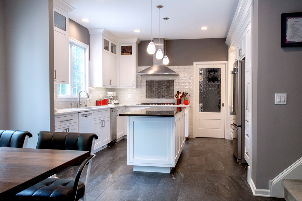 Photo of an eat-in kitchen in New York with recessed-panel cabinets, white cabinets, marble benchtops, white splashback, subway tile splashback, stainless steel appliances, porcelain floors, with island, grey floor and white benchtop.