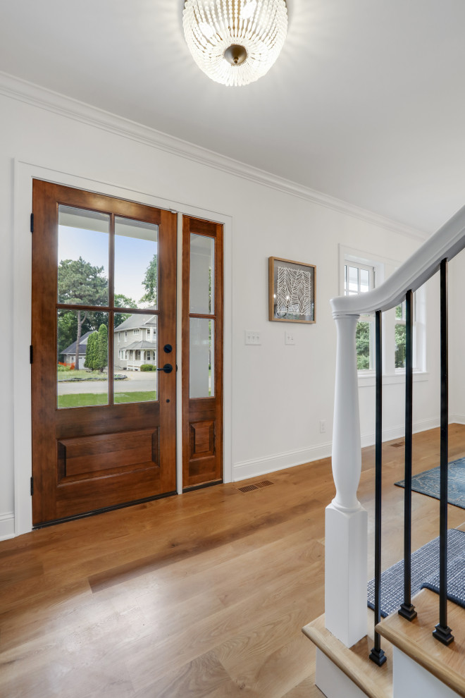 Inspiration for a mid-sized transitional foyer in Minneapolis with white walls, light hardwood floors, a single front door and a medium wood front door.