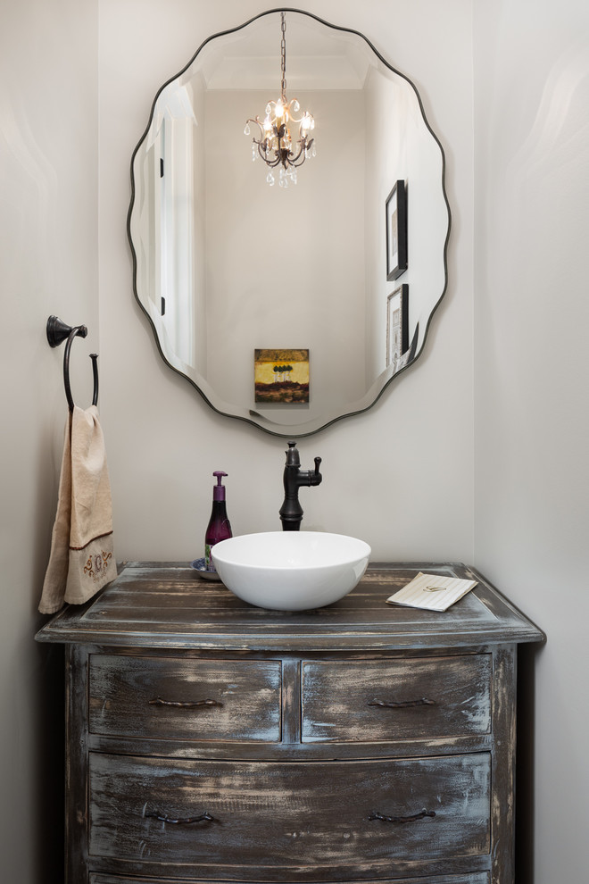 This is an example of a small traditional powder room in Birmingham with furniture-like cabinets, distressed cabinets, a vessel sink, wood benchtops and grey walls.