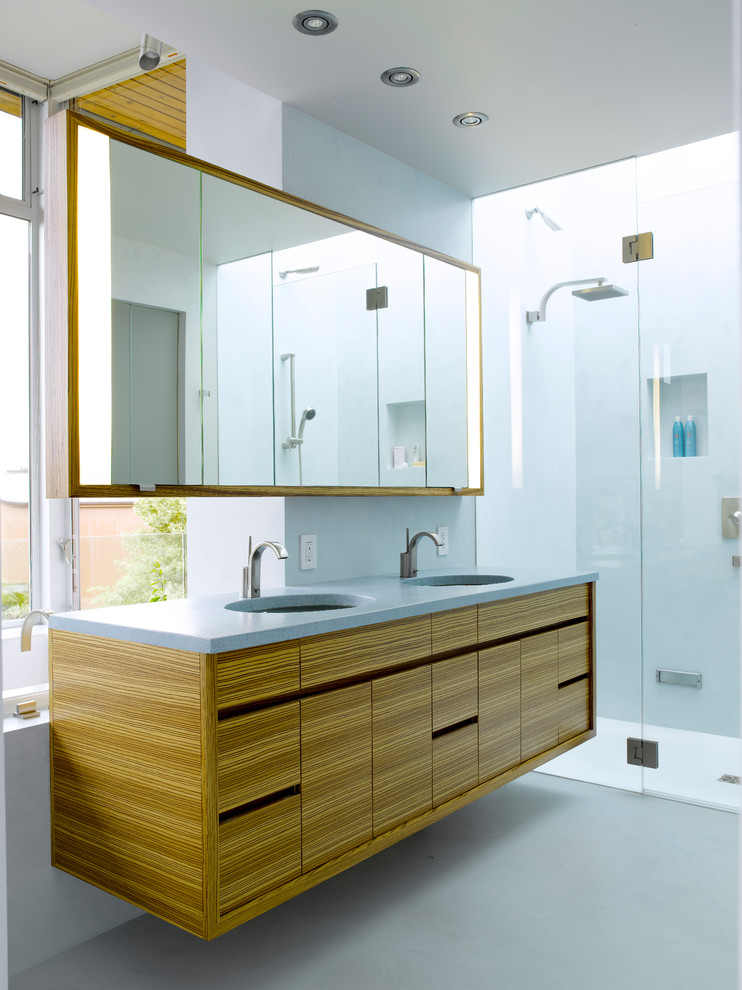 This is an example of a mid-sized modern master bathroom in Seattle with flat-panel cabinets, medium wood cabinets, an undermount sink, a curbless shower, solid surface benchtops, blue walls and concrete floors.