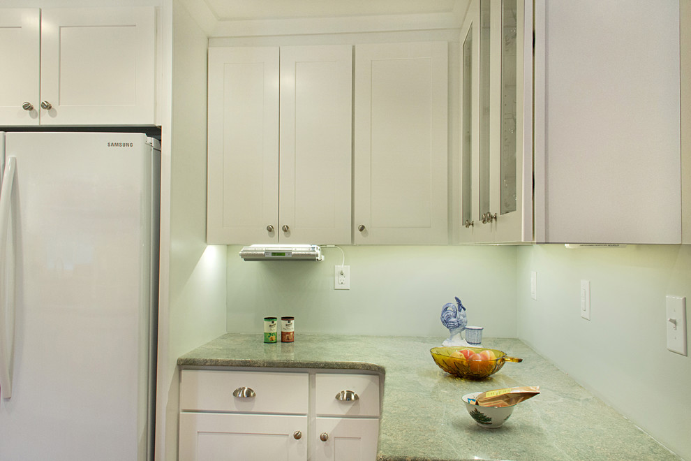 Eat-in kitchen - transitional l-shaped eat-in kitchen idea with an undermount sink, shaker cabinets, white cabinets, granite countertops, green backsplash, glass tile backsplash and white appliances
