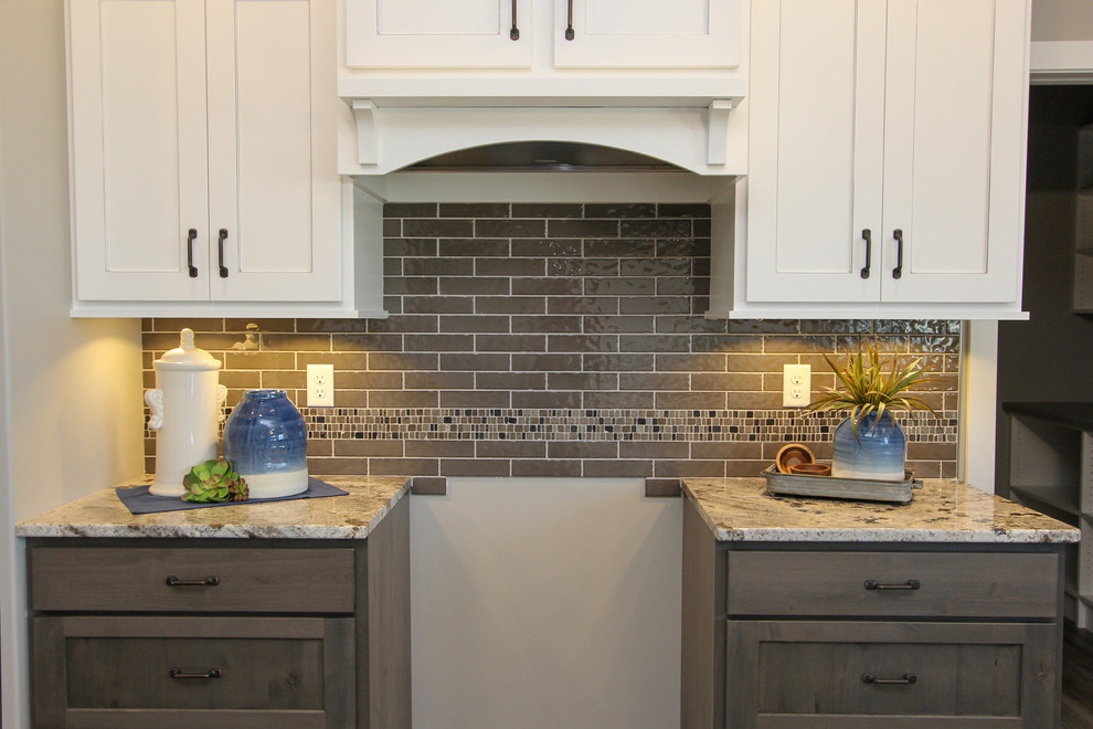 Mid-sized transitional l-shaped laminate floor and brown floor eat-in kitchen photo in Minneapolis with an undermount sink, shaker cabinets, white cabinets, granite countertops, gray backsplash, ceramic backsplash, an island and multicolored countertops