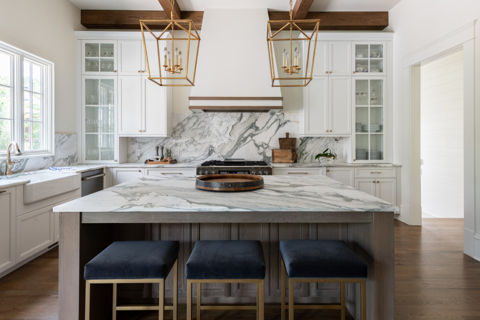 Modern inredning av ett vit vitt kök och matrum, med en rustik diskho, luckor med infälld panel, vita skåp, marmorbänkskiva, vitt stänkskydd, stänkskydd i marmor, rostfria vitvaror, mellanmörkt trägolv, en köksö och brunt golv