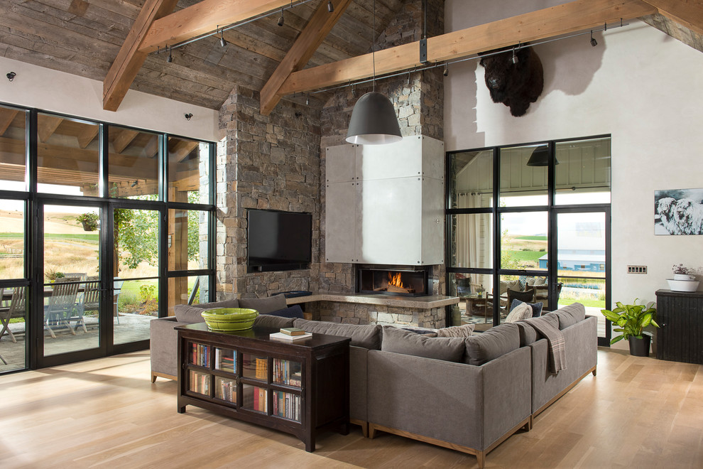 Photo of a large country formal open concept living room in Other with white walls, light hardwood floors, a wood stove, a stone fireplace surround and a built-in media wall.