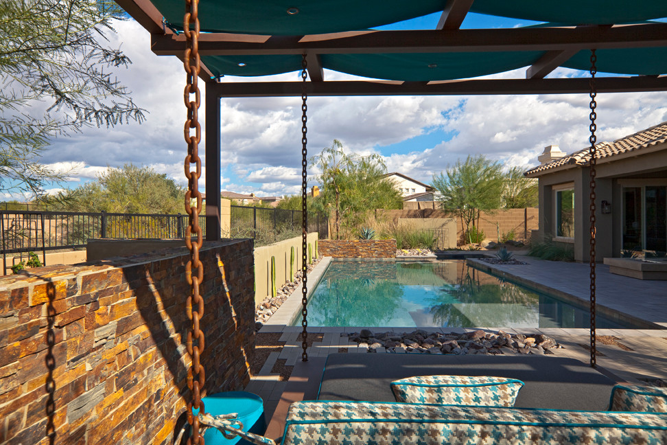 Example of a mid-sized minimalist backyard stone and rectangular pool design