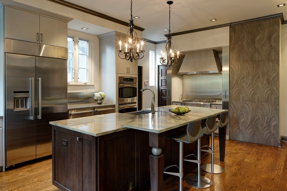 Photo of a large contemporary l-shaped eat-in kitchen in Chicago with a farmhouse sink, flat-panel cabinets, grey cabinets, quartzite benchtops, stainless steel appliances, medium hardwood floors, with island and metallic splashback.
