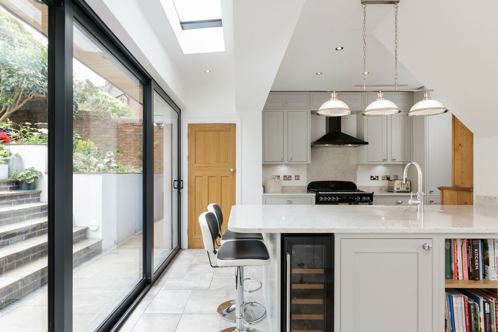 This is an example of a medium sized contemporary single-wall kitchen with a submerged sink, grey cabinets, grey splashback, an island, grey floors, white worktops, shaker cabinets and black appliances.