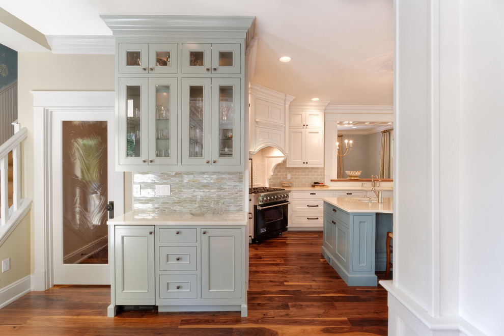 This is an example of a mid-sized traditional single-wall wet bar in Cincinnati with glass-front cabinets, grey cabinets, granite benchtops, grey splashback, glass tile splashback, medium hardwood floors, no sink and brown floor.