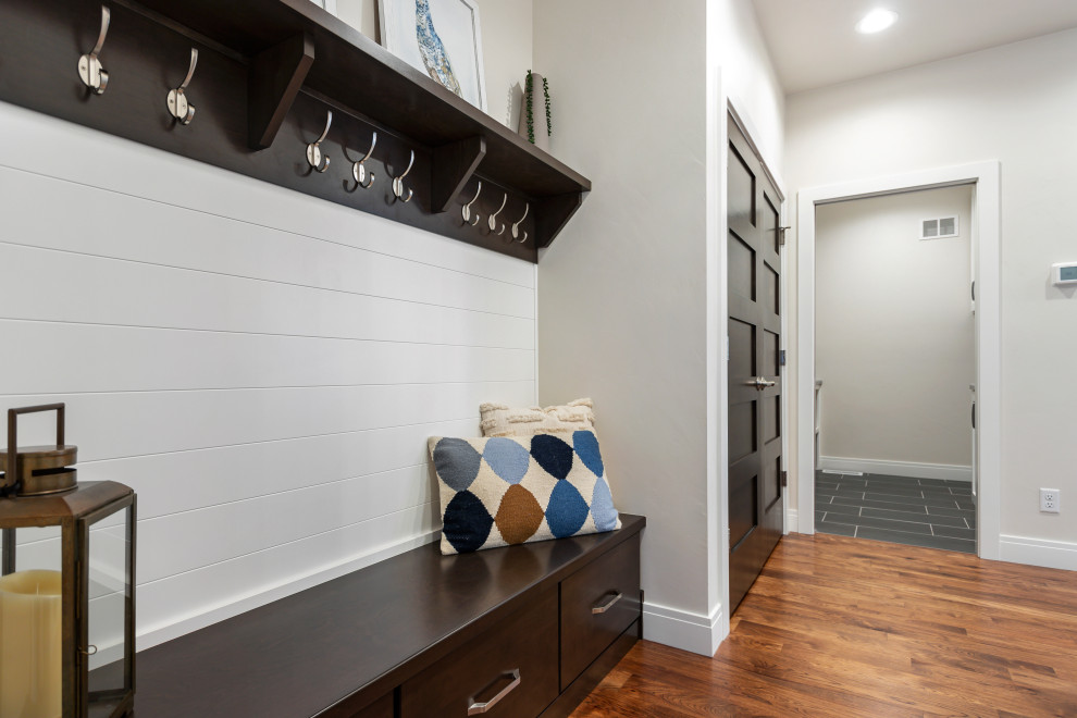 Inspiration for a mid-sized transitional medium tone wood floor and brown floor mudroom remodel with white walls