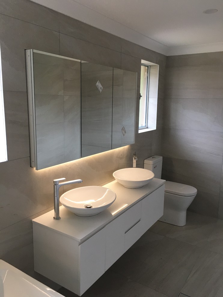 Large modern master bathroom in Melbourne with furniture-like cabinets, white cabinets, a freestanding tub, a one-piece toilet, beige tile, beige walls, quartzite benchtops, a corner shower, ceramic tile, ceramic floors, a vessel sink, beige floor and an open shower.