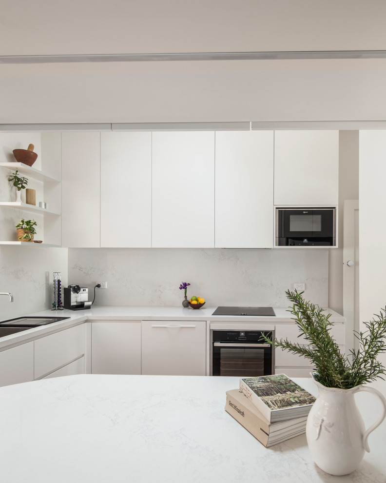 Design ideas for a mid-sized contemporary galley separate kitchen in Melbourne with a double-bowl sink, flat-panel cabinets, white cabinets, quartz benchtops, white splashback, engineered quartz splashback, white appliances, cork floors, a peninsula, brown floor and white benchtop.
