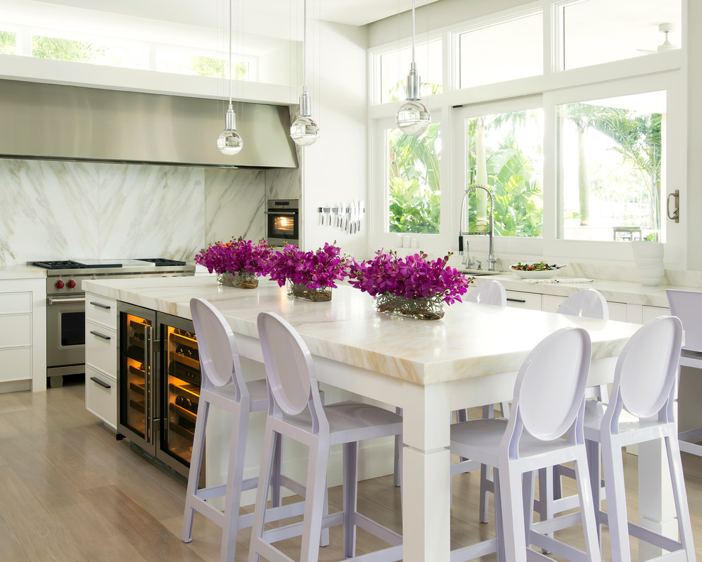 Inspiration for a large contemporary u-shaped separate kitchen in Miami with white cabinets, white splashback, stainless steel appliances, with island, an undermount sink, recessed-panel cabinets, marble benchtops and light hardwood floors.