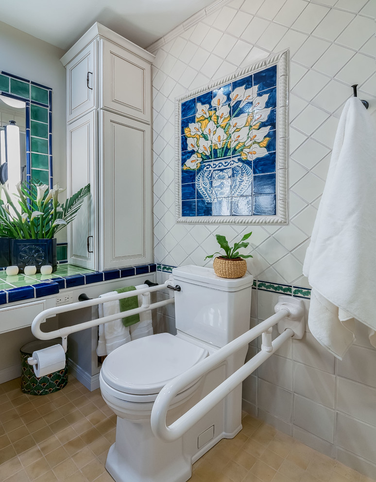 This is an example of a mid-sized traditional master bathroom in San Diego with raised-panel cabinets, white cabinets, a two-piece toilet, ceramic tile, white walls, porcelain floors, an integrated sink, tile benchtops, a curbless shower, white tile, beige floor, an open shower and green benchtops.
