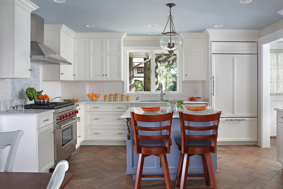 Photo of a mid-sized traditional l-shaped separate kitchen in New York with an undermount sink, recessed-panel cabinets, white cabinets, with island, brown floor, white benchtop, quartz benchtops, white splashback, subway tile splashback, stainless steel appliances and porcelain floors.