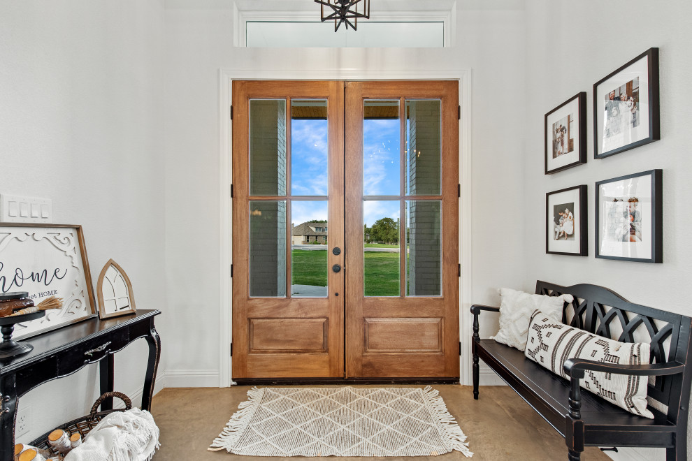 Mittelgroßes Landhausstil Foyer mit weißer Wandfarbe, Betonboden, Doppeltür, hellbrauner Holzhaustür und beigem Boden in Dallas