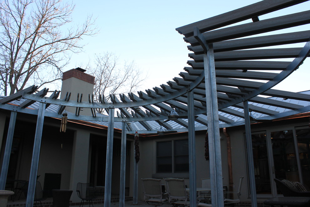 Photo of a large industrial backyard patio in Austin with brick pavers and a pergola.