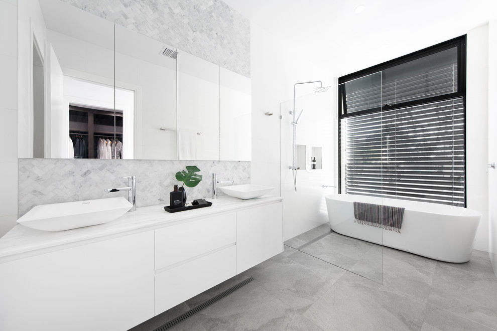 Photo of a contemporary master wet room bathroom in Melbourne with flat-panel cabinets, white cabinets, gray tile, white benchtops, a freestanding tub, white walls, a vessel sink, grey floor and an open shower.