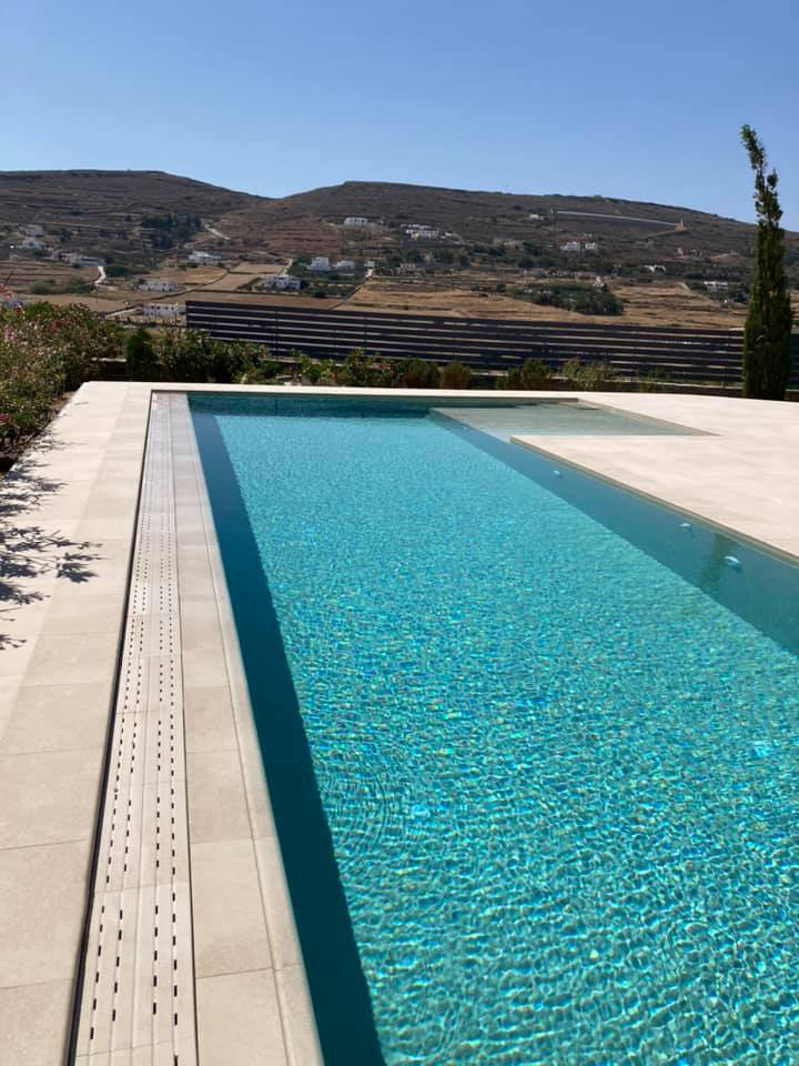 Diseño de piscina alargada minimalista grande rectangular en patio con paisajismo de piscina y suelo de baldosas
