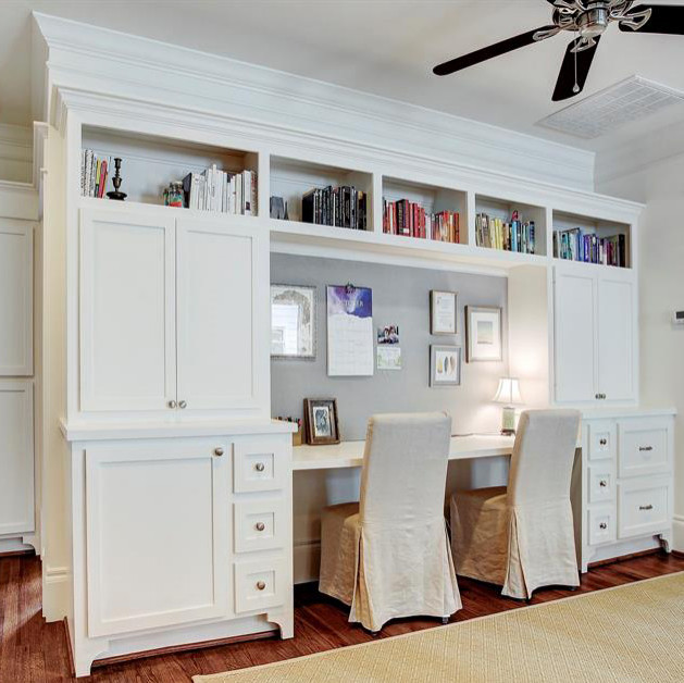 Design ideas for a mid-sized transitional home office in Houston with white walls, medium hardwood floors, a built-in desk and brown floor.
