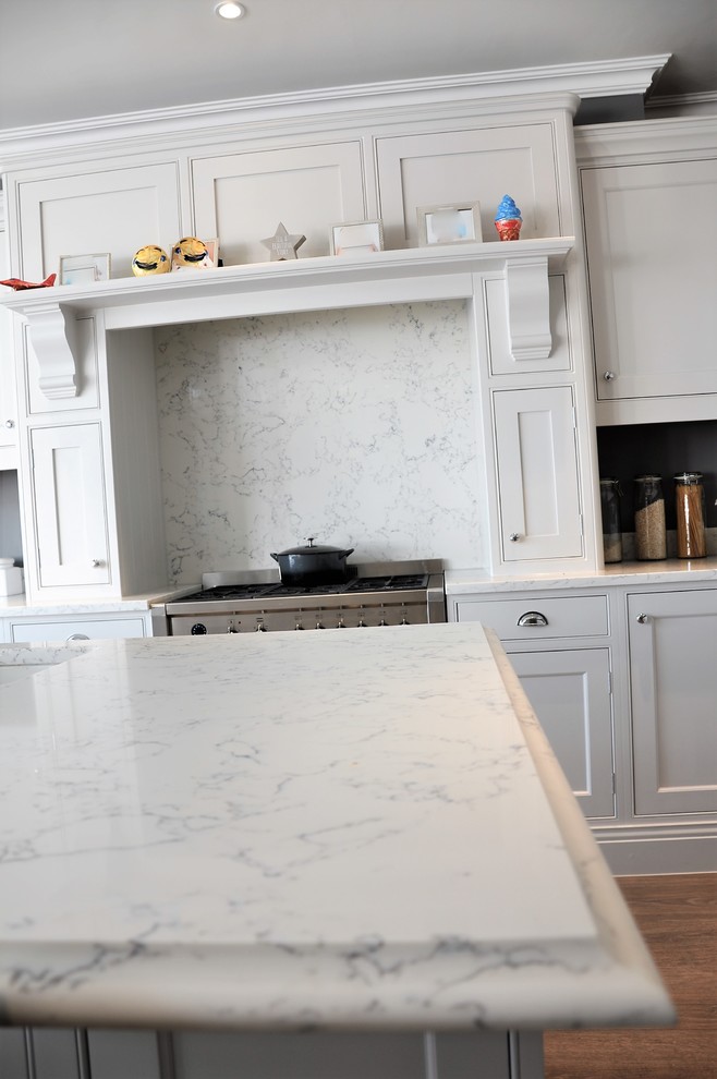 Idéer för att renovera ett stort vintage vit vitt kök, med en dubbel diskho, skåp i shakerstil, grå skåp, bänkskiva i kvartsit, vitt stänkskydd, stänkskydd i sten, rostfria vitvaror, laminatgolv, en köksö och brunt golv