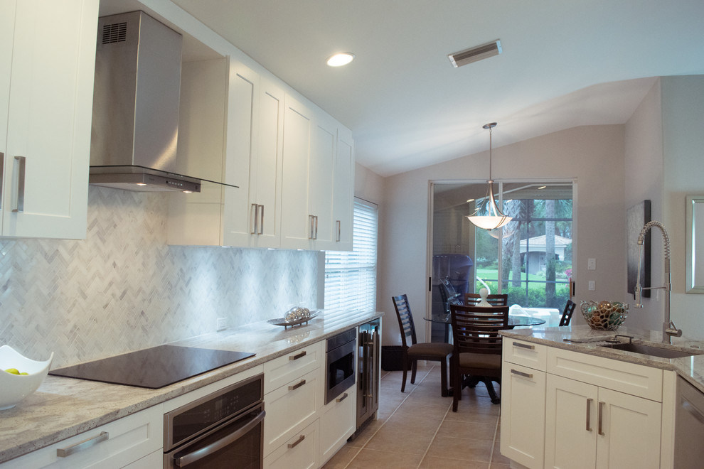 Inspiration for a mid-sized transitional galley ceramic tile and beige floor eat-in kitchen remodel in Miami with an undermount sink, shaker cabinets, white cabinets, granite countertops, gray backsplash, stone tile backsplash, stainless steel appliances and a peninsula