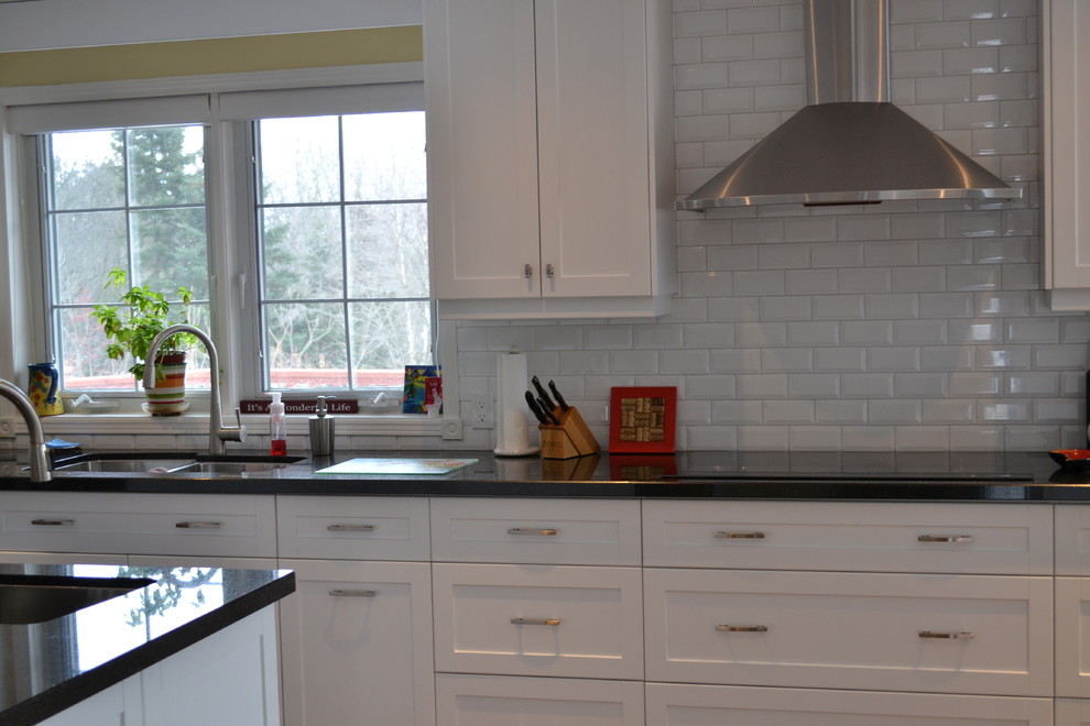 Example of a large transitional galley medium tone wood floor eat-in kitchen design in Toronto with a double-bowl sink, shaker cabinets, white cabinets, granite countertops, white backsplash, subway tile backsplash, stainless steel appliances and an island