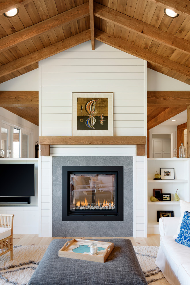 Photo of a mid-sized country open concept family room in Minneapolis with white walls, light hardwood floors, a two-sided fireplace, a concrete fireplace surround, a corner tv and brown floor.