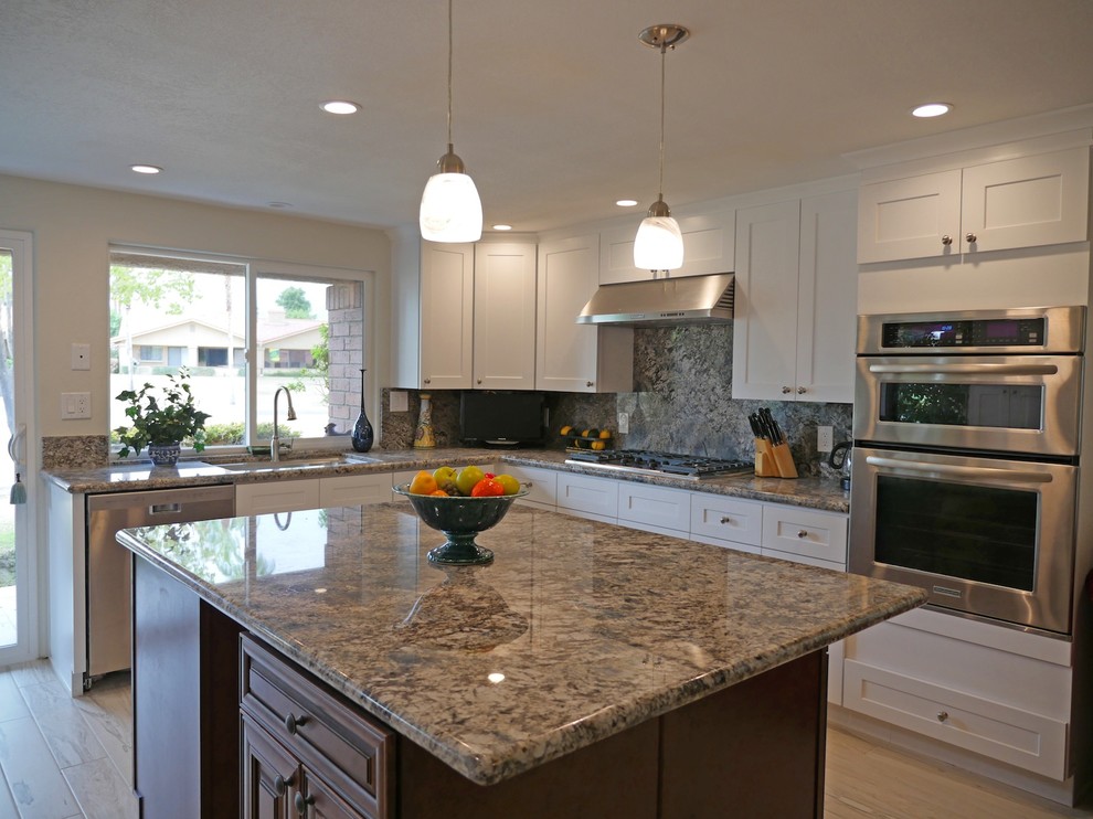 This is an example of a mid-sized traditional l-shaped eat-in kitchen in Los Angeles with medium wood cabinets, granite benchtops, grey splashback, stainless steel appliances, ceramic floors and with island.