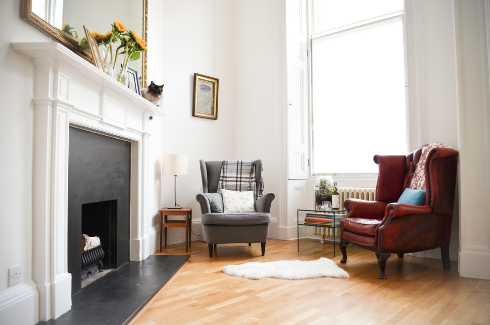 Photo of a small traditional formal open concept living room in Edinburgh with a standard fireplace, no tv, white walls, medium hardwood floors and a stone fireplace surround.