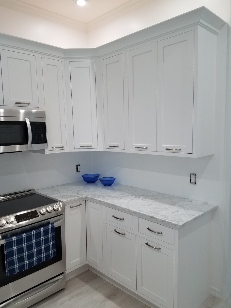 Inspiration for a mid-sized transitional u-shaped laminate floor and white floor kitchen remodel in Miami with a farmhouse sink, flat-panel cabinets, white cabinets, marble countertops, white backsplash, cement tile backsplash, stainless steel appliances, an island and white countertops