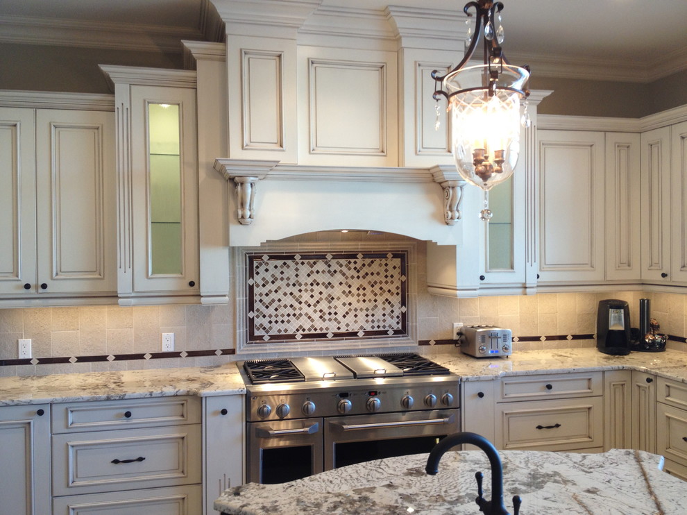 Inspiration for a large timeless u-shaped open concept kitchen remodel in Edmonton with an undermount sink, raised-panel cabinets, white cabinets, granite countertops, beige backsplash, stone tile backsplash, stainless steel appliances and an island