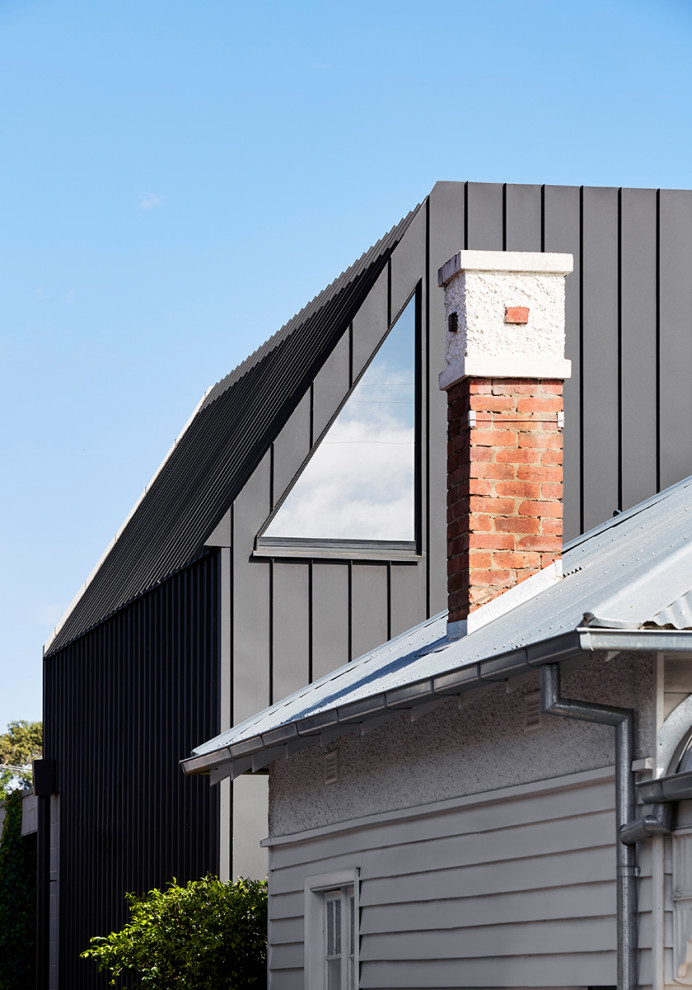 Example of a mid-sized trendy black two-story house exterior design in Melbourne with a metal roof and a black roof