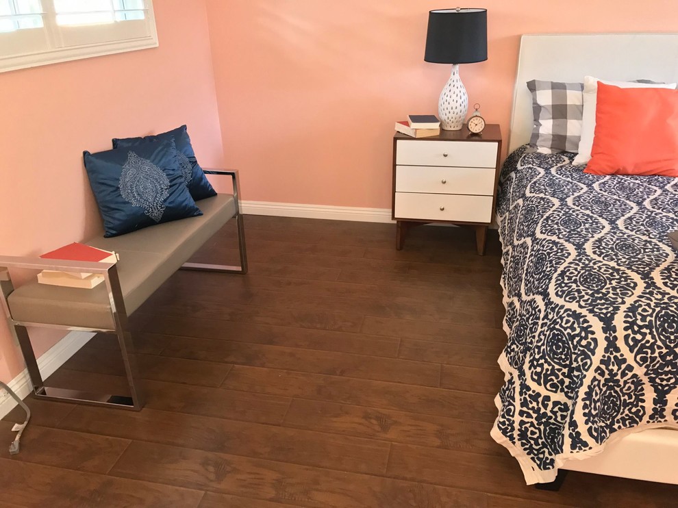 This is an example of a mid-sized transitional bedroom in Orange County with pink walls, dark hardwood floors, no fireplace and brown floor.