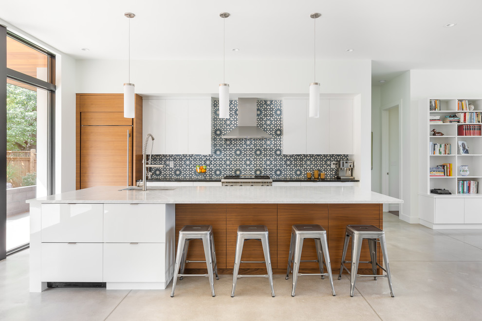 Contemporary galley open plan kitchen in Denver with an undermount sink, flat-panel cabinets, medium wood cabinets, multi-coloured splashback, panelled appliances, concrete floors, with island, beige floor, white benchtop, stone tile splashback and marble benchtops.