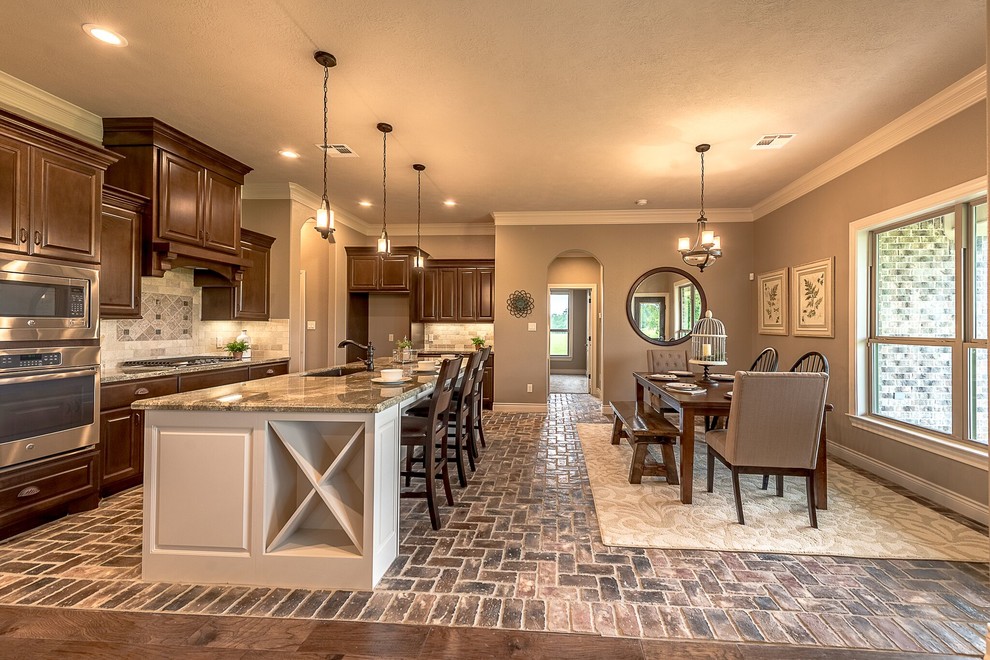 Open concept kitchen - mid-sized rustic u-shaped brick floor and brown floor open concept kitchen idea in Austin with a farmhouse sink, shaker cabinets, medium tone wood cabinets, granite countertops, beige backsplash, travertine backsplash, stainless steel appliances and an island