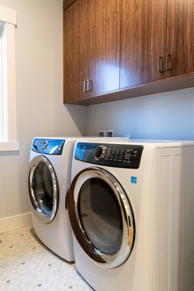 Medium sized modern galley separated utility room in Other with flat-panel cabinets, medium wood cabinets, grey walls, vinyl flooring, a side by side washer and dryer and grey floors.