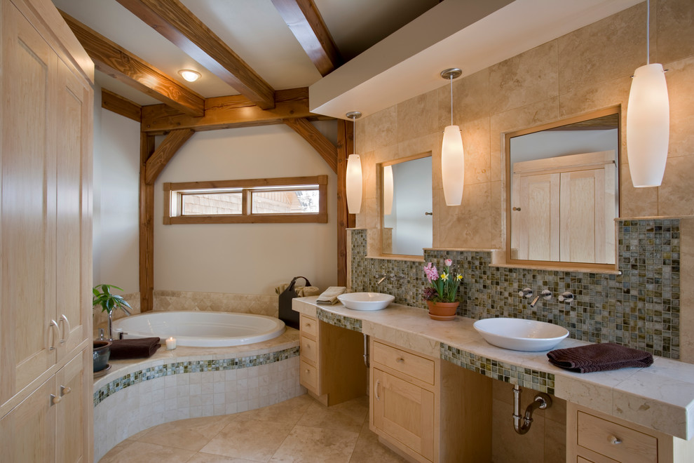 Photo of a mid-sized country master bathroom in Boise with a vessel sink, flat-panel cabinets, light wood cabinets, limestone benchtops, a corner tub, multi-coloured tile, ceramic tile, white walls and travertine floors.