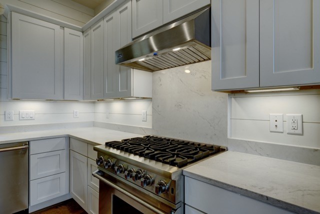 Kitchen - mid-sized rustic u-shaped medium tone wood floor and brown floor kitchen idea with an undermount sink, shaker cabinets, white cabinets, quartz countertops, white backsplash, wood backsplash, stainless steel appliances and an island