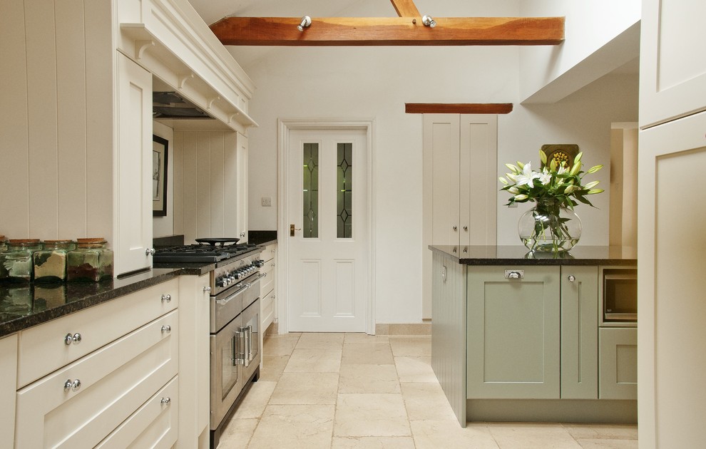 This is an example of a mid-sized traditional l-shaped eat-in kitchen in Oxfordshire with a single-bowl sink, shaker cabinets, white cabinets, granite benchtops, stainless steel appliances, ceramic floors and with island.