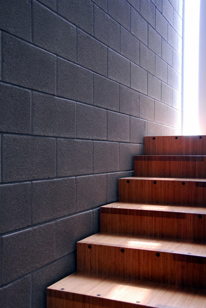 Imagen de escalera recta minimalista grande con escalones de madera, contrahuellas de madera y barandilla de madera