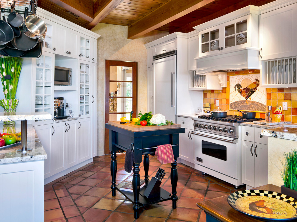 Inspiration for a country u-shaped separate kitchen in Montreal with shaker cabinets, white cabinets, multi-coloured splashback, white appliances, terra-cotta floors and with island.